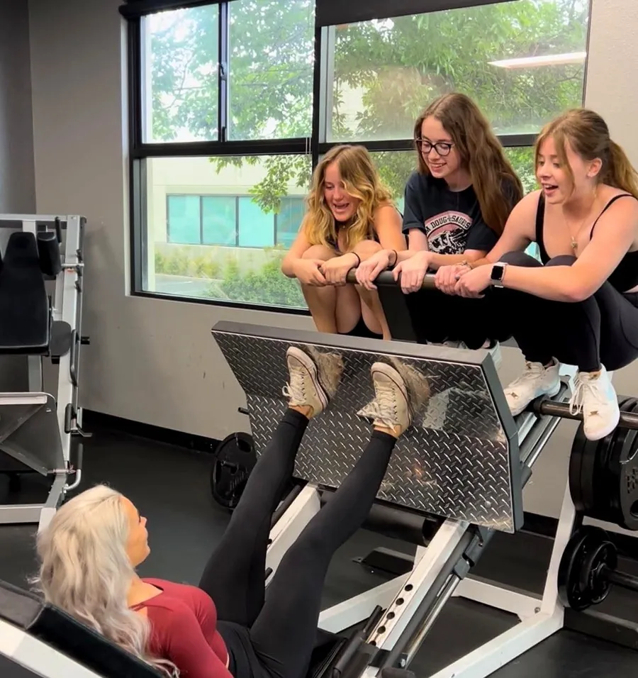 Members laughing together at the leg press machine