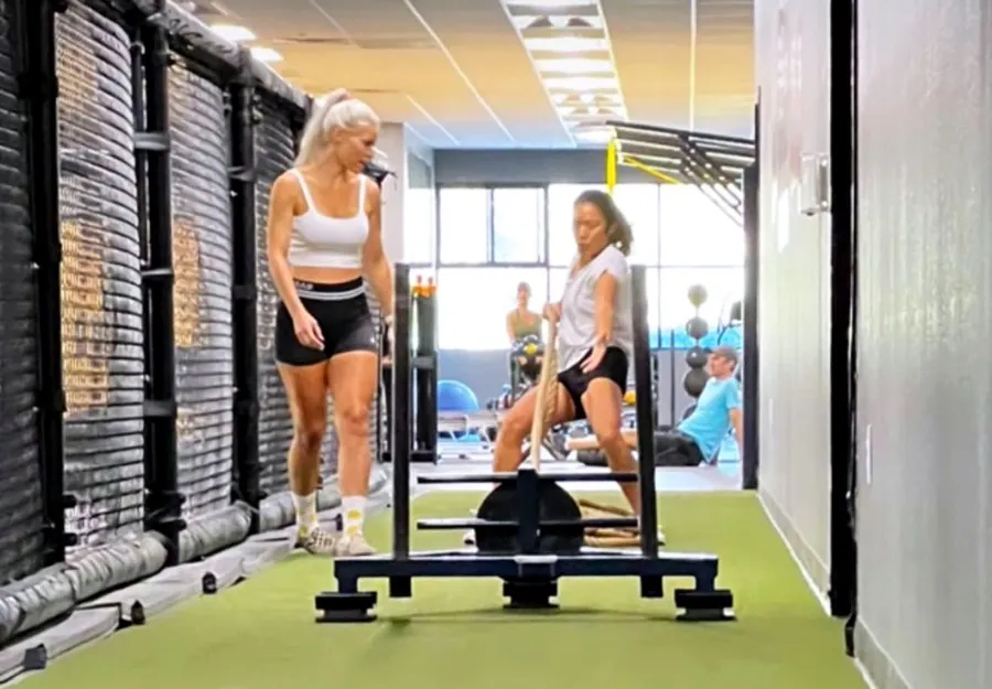 Two members pulling a weighted sled together in the training hallway