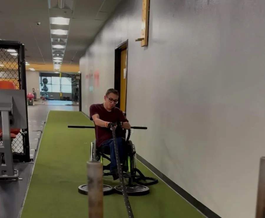An athlete using adaptive rope-pull equipment in a wheelchair at Valor Fit Society
