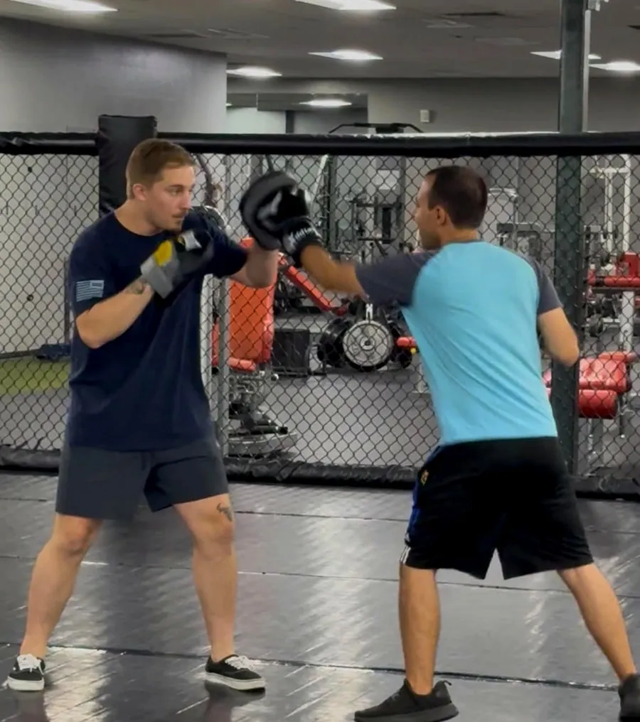 Two members doing pad work together in the training cage